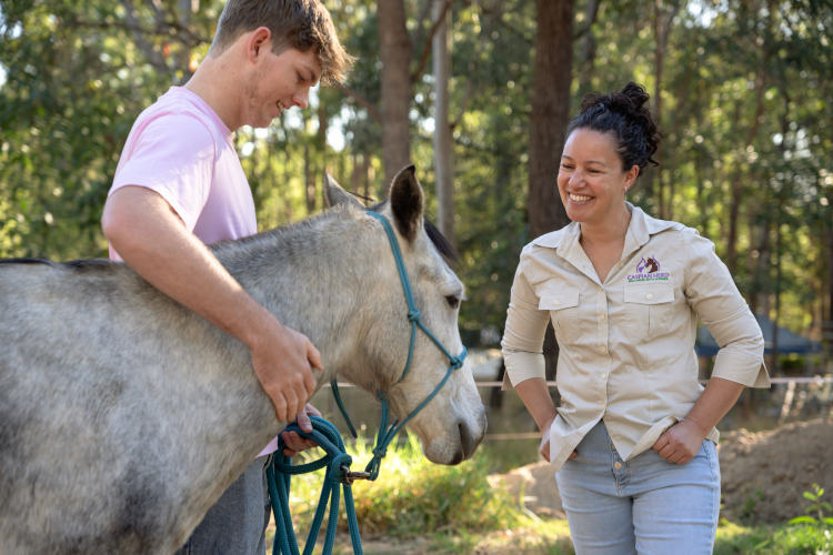 Young Brisbane equine therapy student patting a grey horse