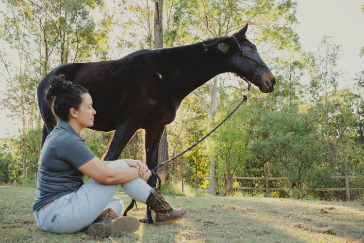 equine assisted therapy practitioner sitting beside her horse
